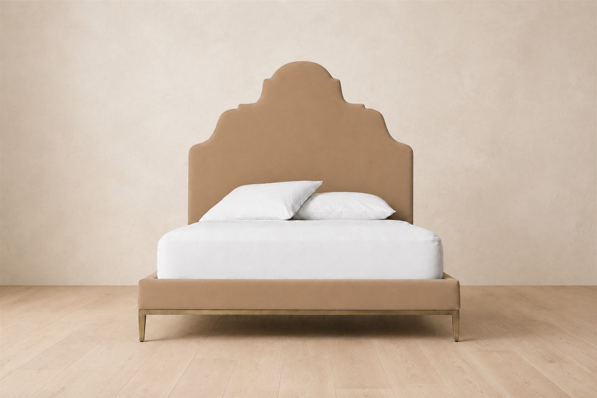Camilla Upholstered Bed — Aged Brass, photographed in a quiet bedroom