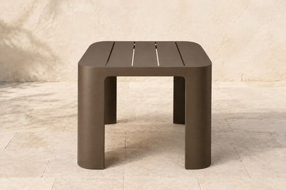 Serein Dining Table in Aluminium, photographed in a quiet outdoor courtyard