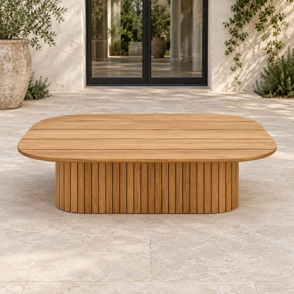 Lifestyle view: Ethereal Coffee Table in Teak, straight frontal view in a planted home courtyard