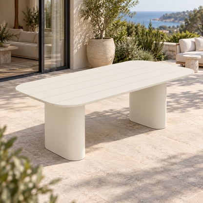 Lifestyle view: Ripple Dining Table in Aluminium, opposite elevated diagonal beside a furnished coastal home